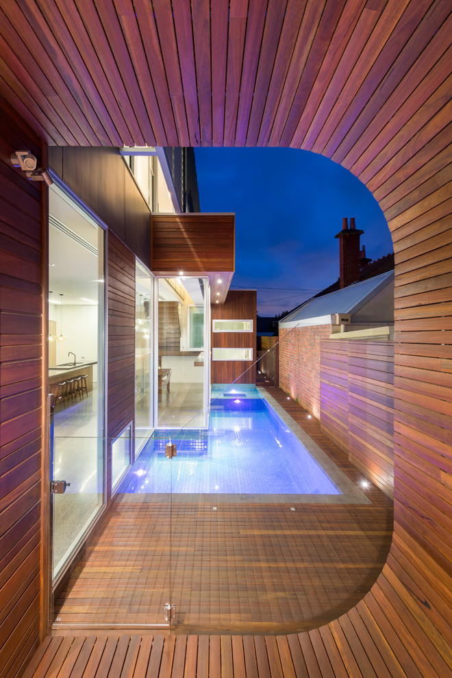 Foto de piscina contemporánea rectangular en patio lateral con entablado