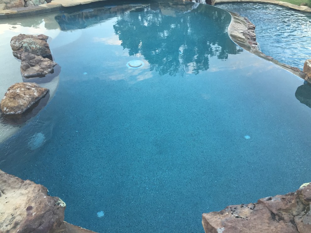 Пример оригинального дизайна: большой бассейн-инфинити произвольной формы на заднем дворе в морском стиле с водной горкой и покрытием из декоративного бетона