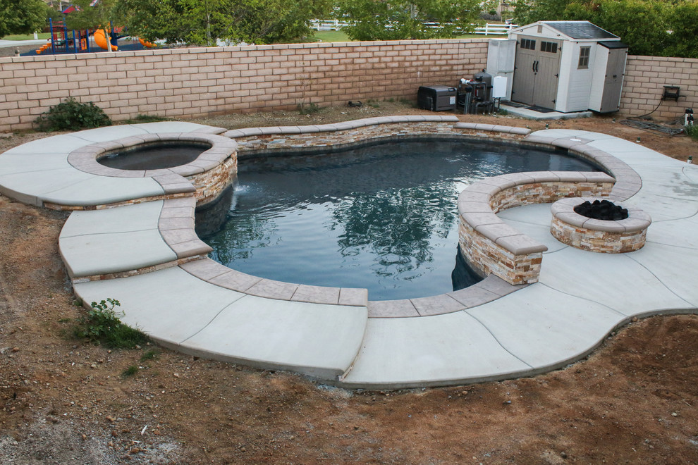 Example of a mid-sized classic backyard concrete and custom-shaped pool design in Los Angeles