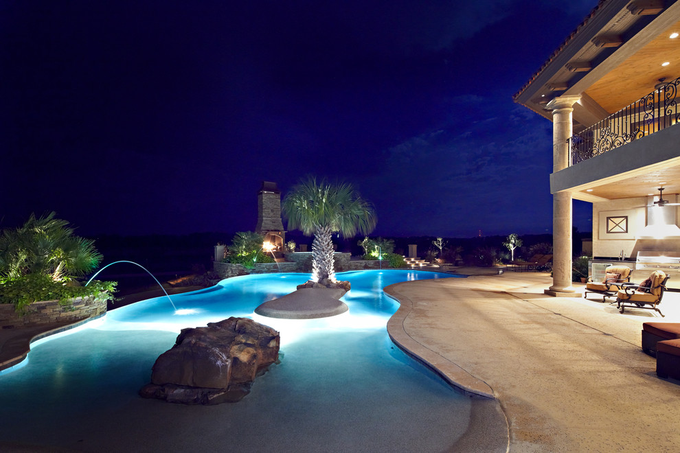 Стильный дизайн: огромный бассейн-инфинити произвольной формы на заднем дворе в средиземноморском стиле с фонтаном и покрытием из декоративного бетона - последний тренд
