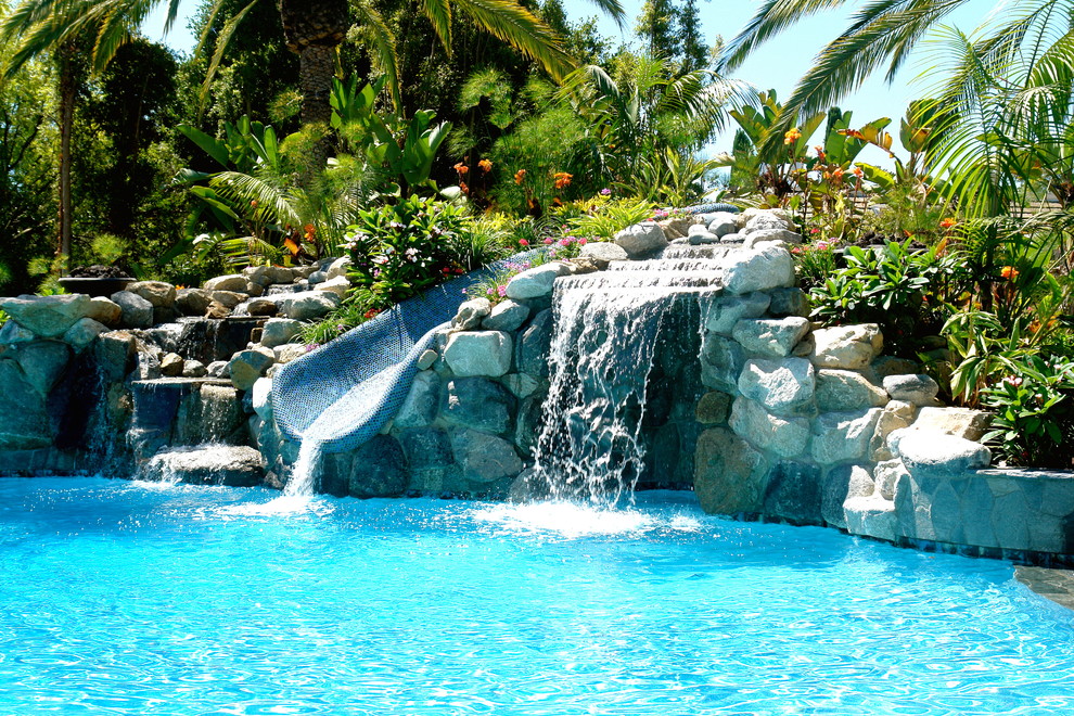This is an example of a world-inspired natural swimming pool in San Diego with a water slide.