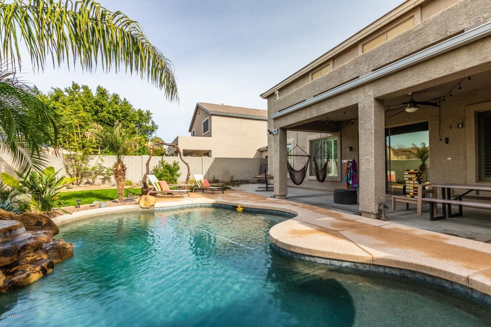 Photo of a medium sized world-inspired back custom shaped swimming pool in Phoenix with a water feature and concrete paving.