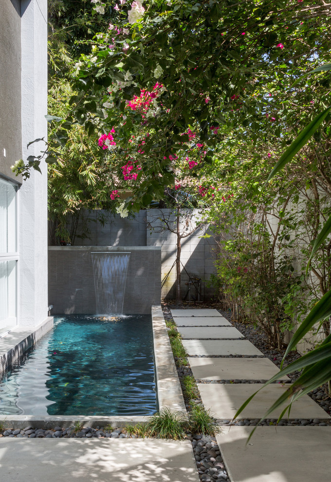 На фото: прямоугольный бассейн-инфинити среднего размера на боковом дворе в стиле модернизм с фонтаном и мощением тротуарной плиткой