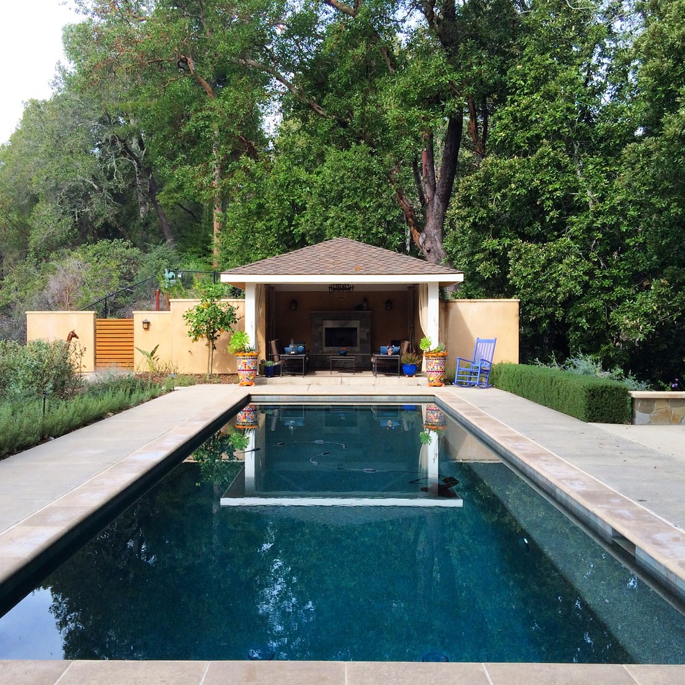Modelo de casa de la piscina y piscina alargada de estilo americano grande rectangular en patio trasero con adoquines de hormigón