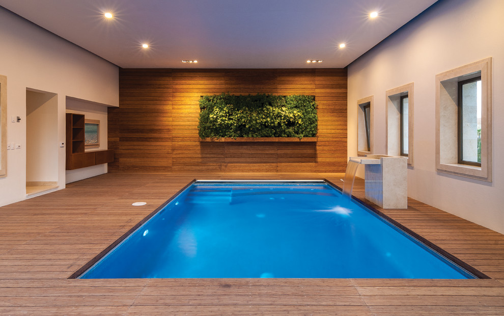 Exemple d'une piscine moderne rectangle avec une terrasse en bois.
