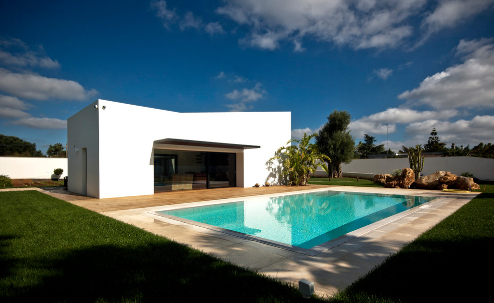 Ejemplo de piscina mediterránea rectangular con adoquines de piedra natural