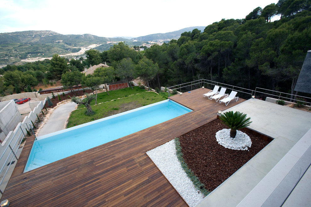 Esempio di una grande piscina a sfioro infinito minimalista rettangolare davanti casa con pedane