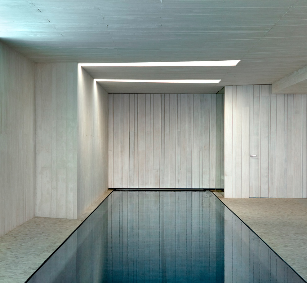 Idee per una grande piscina coperta design rettangolare con una dépendance a bordo piscina e lastre di cemento