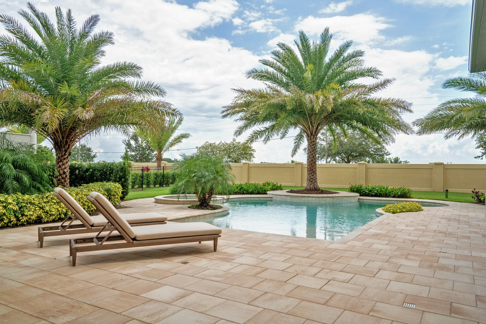 Foto di una grande piscina tropicale personalizzata dietro casa con una vasca idromassaggio e piastrelle