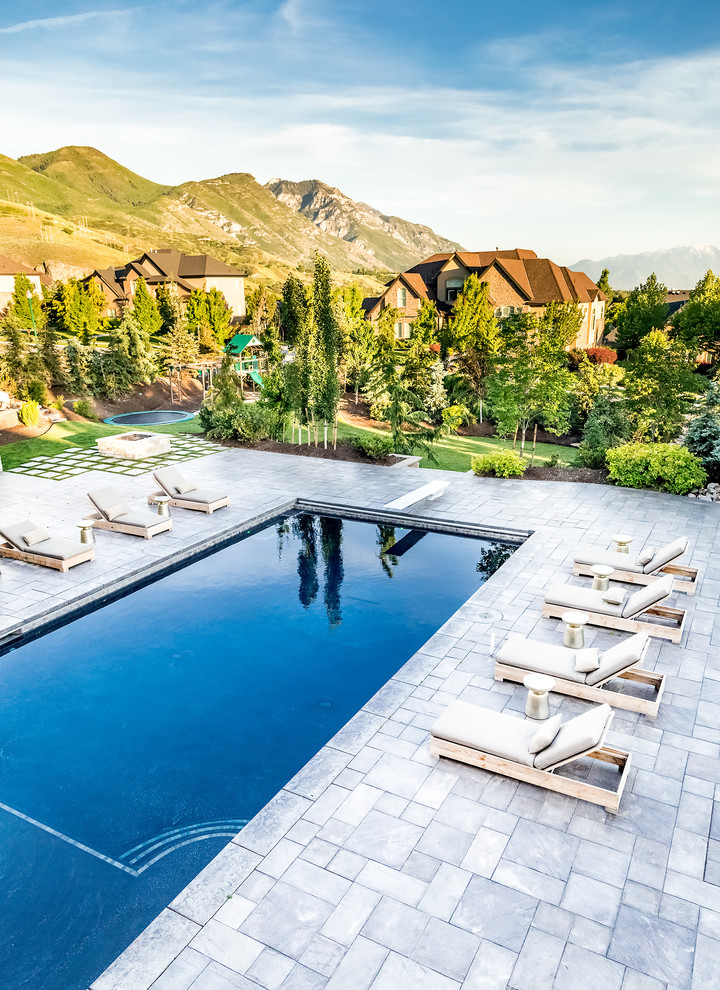 Foto de piscina alargada clásica renovada grande rectangular en patio trasero con adoquines de piedra natural