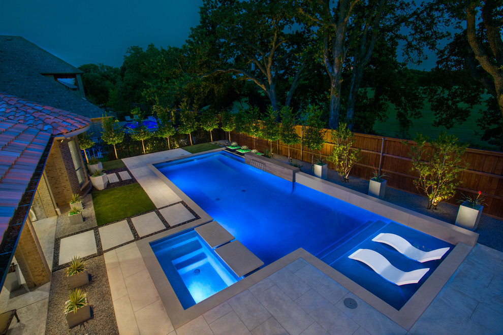 Diseño de piscina con fuente alargada contemporánea rectangular en patio trasero con losas de hormigón