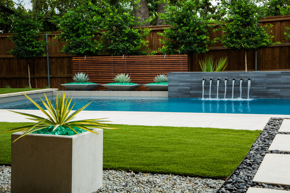 Imagen de piscina con fuente alargada contemporánea rectangular en patio trasero con losas de hormigón