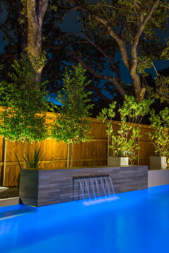 Photo of a contemporary back rectangular lengths swimming pool in Dallas with a water feature and concrete slabs.