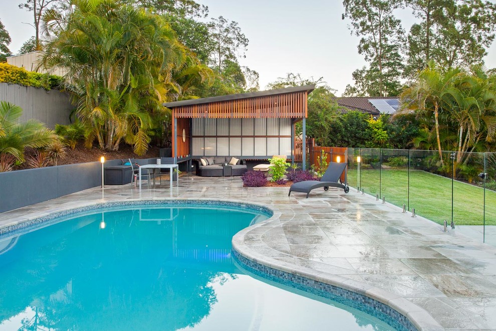 Foto på en mellanstor funkis pool på baksidan av huset, med kakelplattor