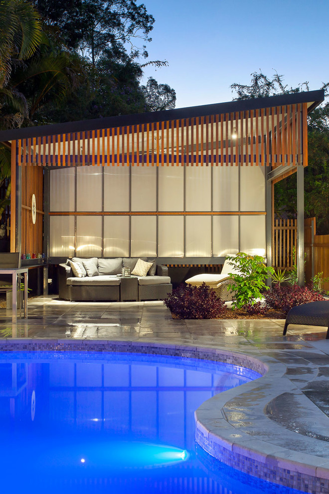 Imagen de piscina contemporánea de tamaño medio tipo riñón en patio trasero con suelo de baldosas