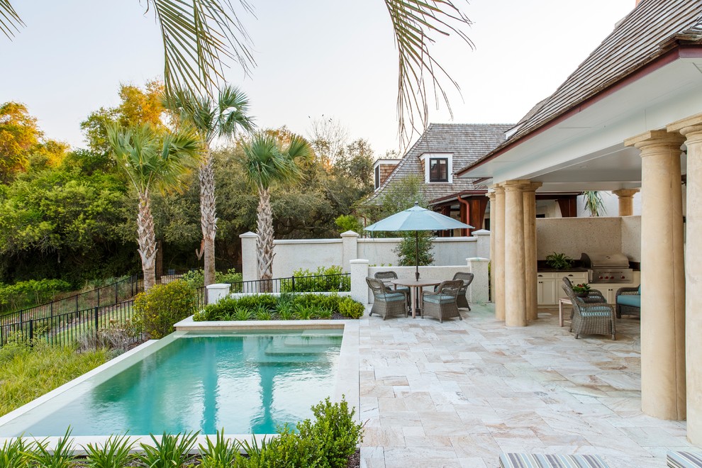 Diseño de piscina infinita clásica pequeña rectangular en patio trasero con adoquines de piedra natural