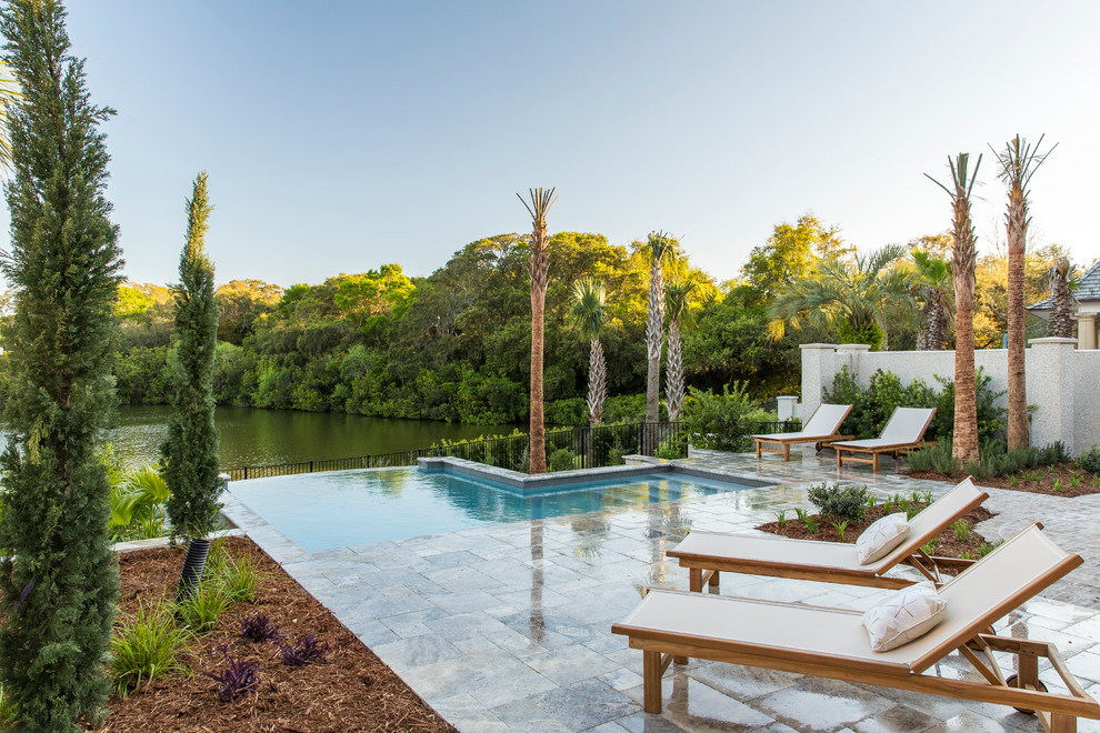 Example of a small classic backyard stone and l-shaped infinity pool design in Charleston