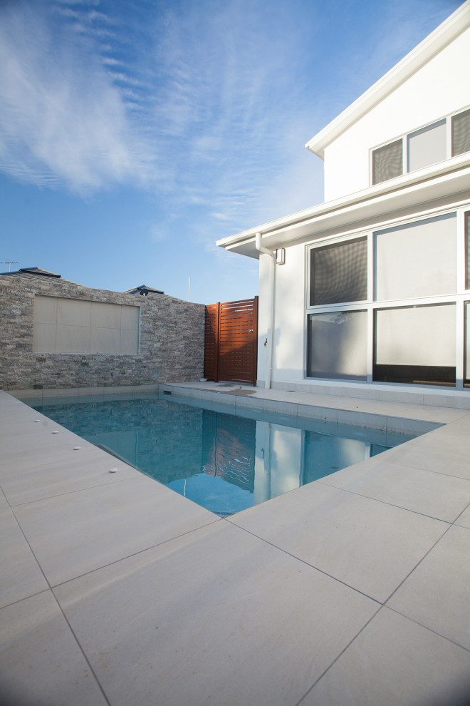 Ispirazione per una piscina monocorsia moderna rettangolare di medie dimensioni e dietro casa con piastrelle