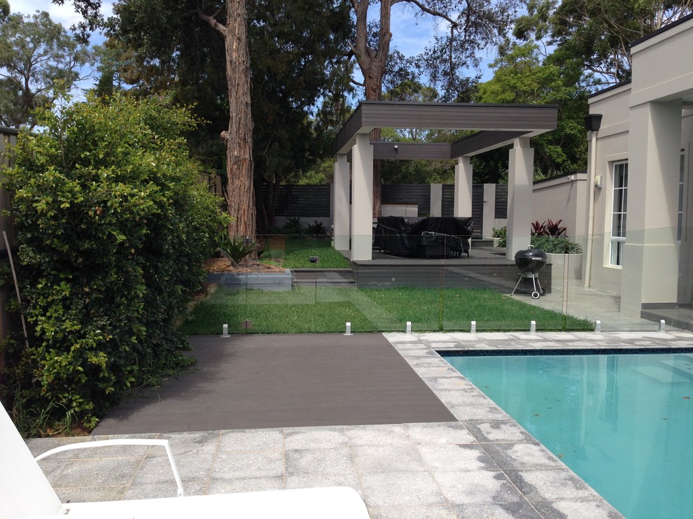 Réalisation d'une grande piscine arrière design rectangle avec des pavés en pierre naturelle.