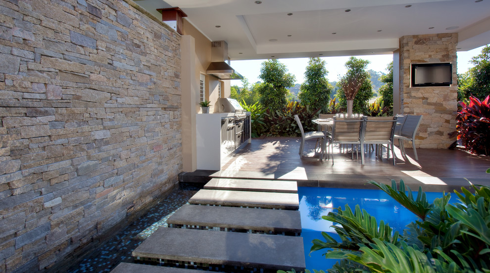 Modelo de casa de la piscina y piscina moderna de tamaño medio a medida en patio trasero con entablado