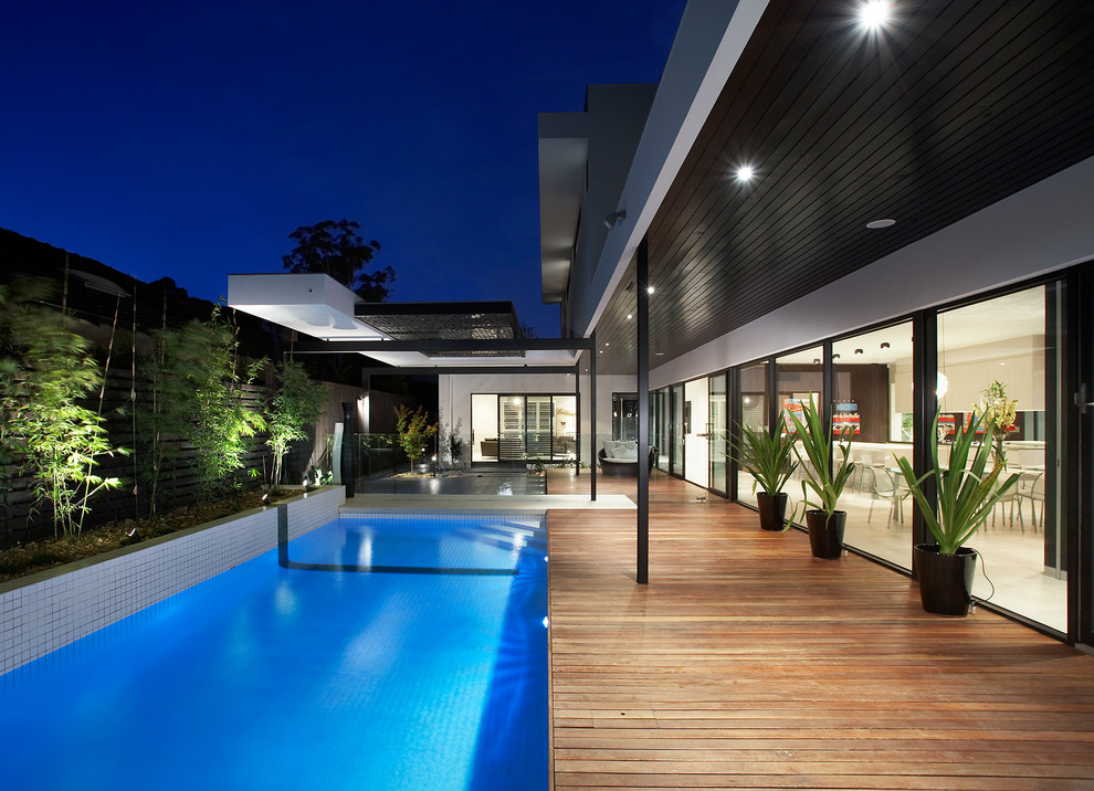 Exemple d'une grande piscine tendance avec une terrasse en bois.