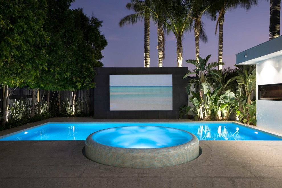 Immagine di una grande piscina monocorsia minimalista rettangolare dietro casa con una vasca idromassaggio e pavimentazioni in pietra naturale