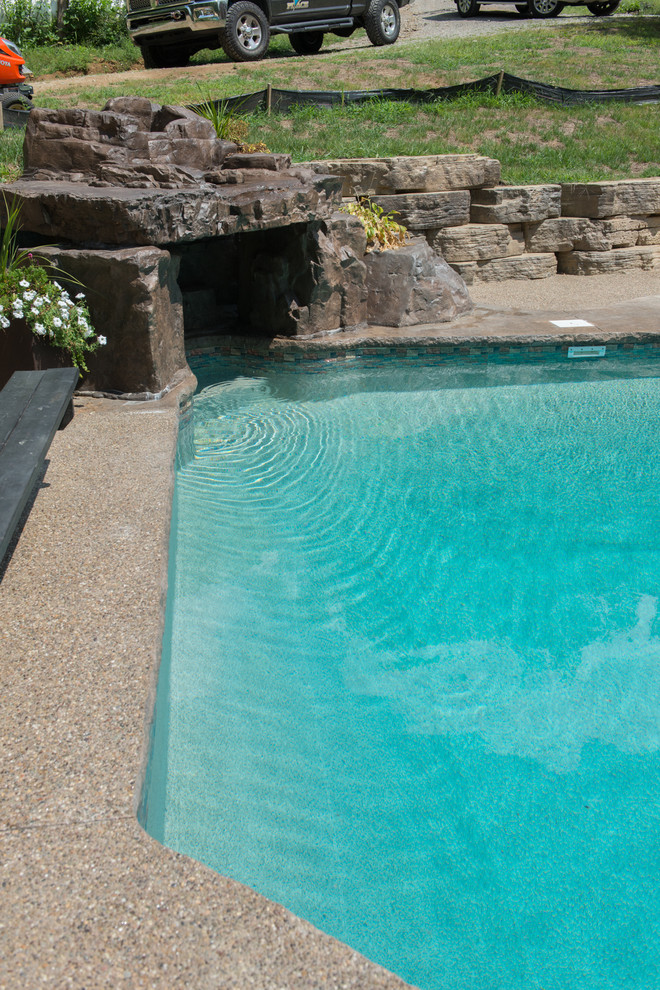 Ejemplo de piscina con fuente natural rural de tamaño medio a medida en patio trasero con suelo de hormigón estampado
