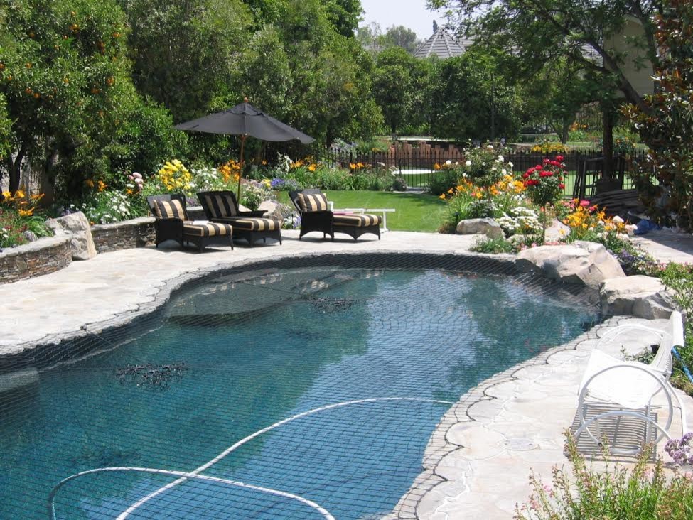 Aménagement d'une grande piscine arrière classique en forme de haricot avec un bain bouillonnant et des pavés en pierre naturelle.