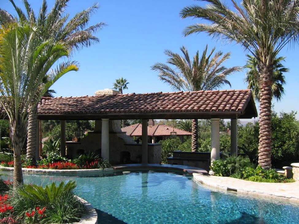 Exempel på en stor klassisk njurformad pool på baksidan av huset, med spabad och naturstensplattor
