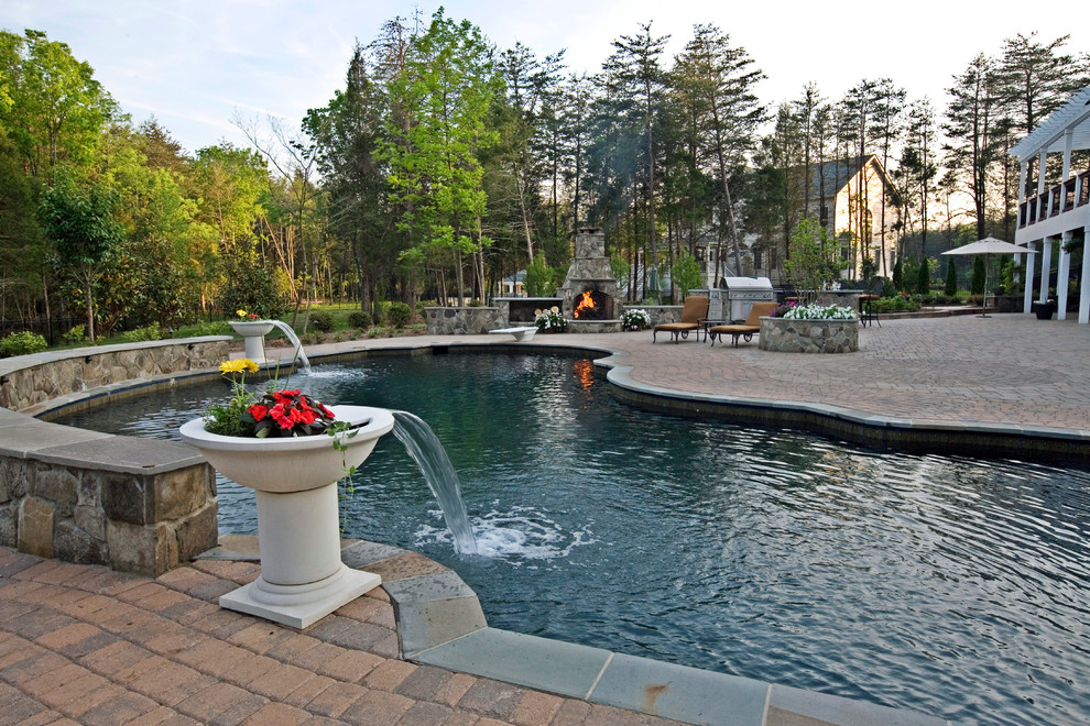 Foto de piscina con fuente tradicional grande a medida en patio trasero con adoquines de ladrillo