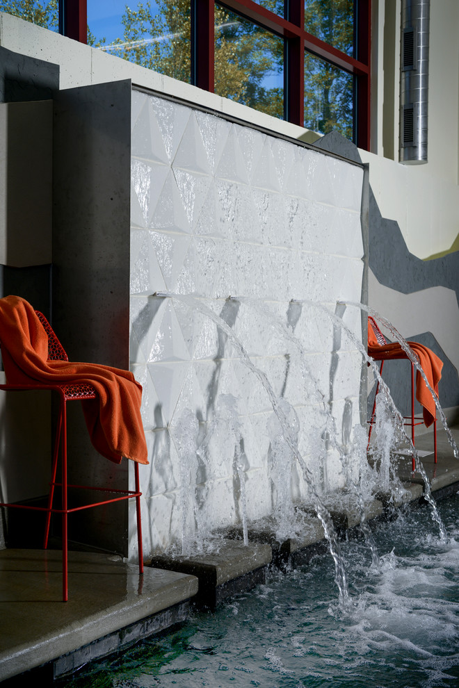 Esempio di una piscina coperta minimalista personalizzata di medie dimensioni con fontane e lastre di cemento