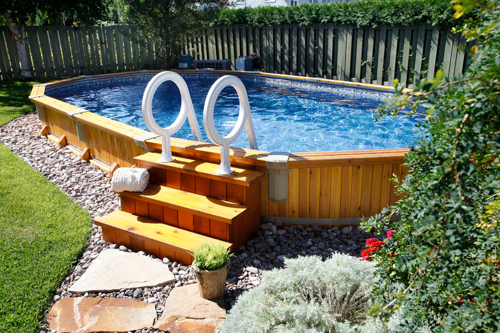 На фото: наземный, круглый бассейн среднего размера на заднем дворе с покрытием из гравия