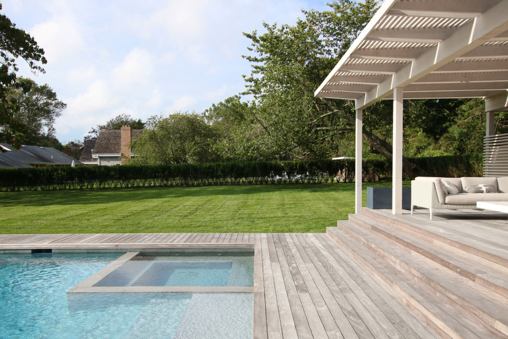 Large minimalist backyard rectangular hot tub photo in New York with decking