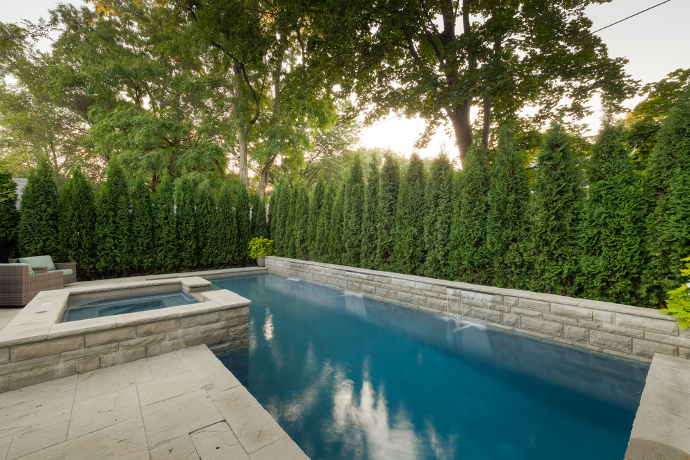 На фото: большой прямоугольный бассейн в классическом стиле с фонтаном и покрытием из каменной брусчатки