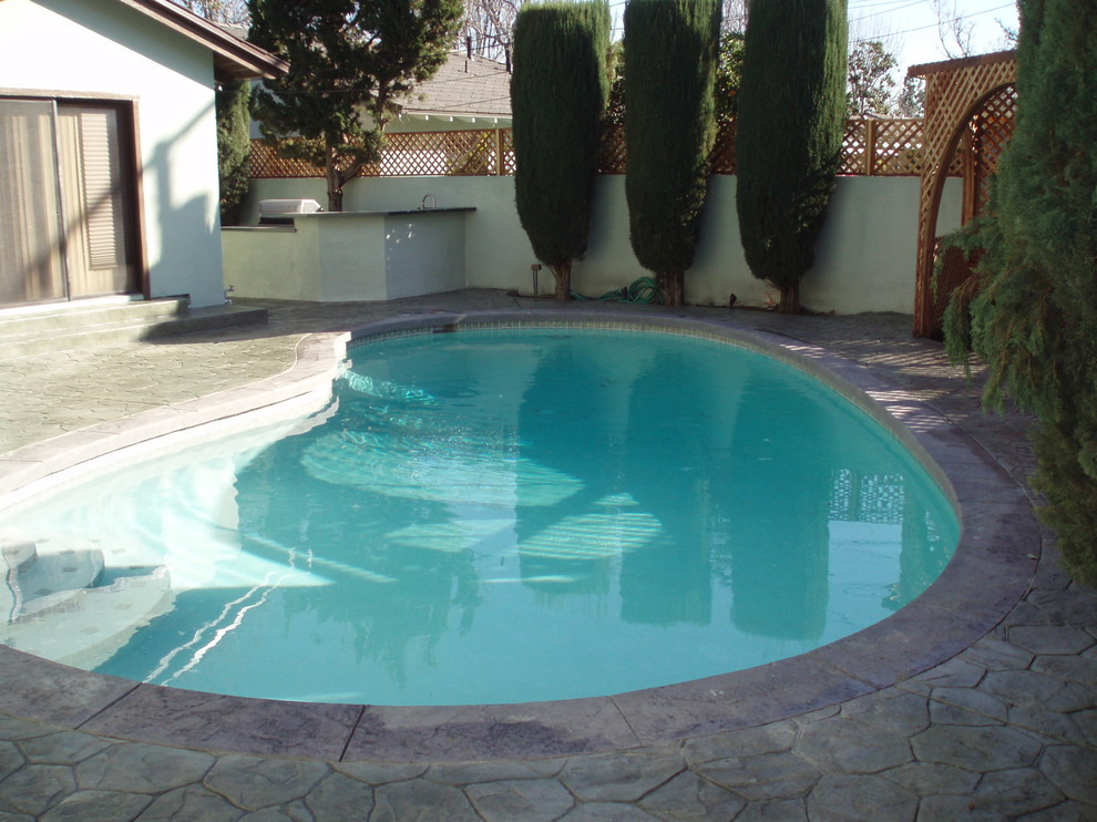 Foto de piscina alargada tradicional renovada de tamaño medio a medida en patio trasero con adoquines de piedra natural