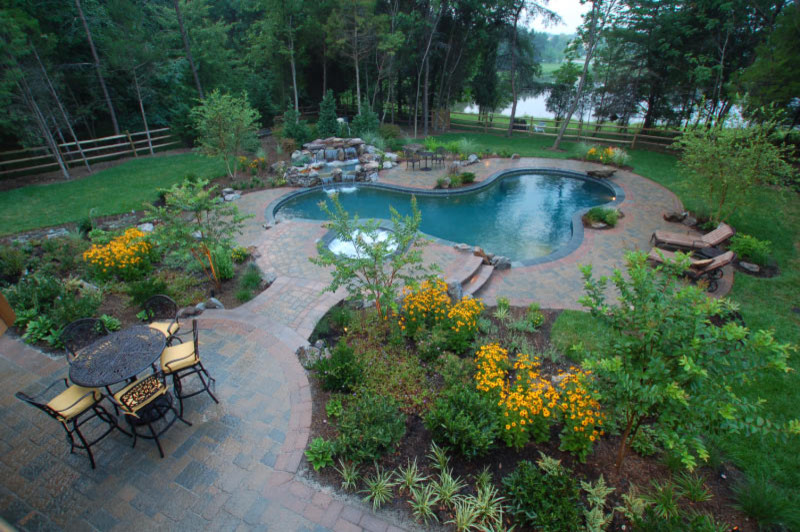 Immagine di una piscina naturale boho chic personalizzata di medie dimensioni e dietro casa con fontane e pavimentazioni in cemento