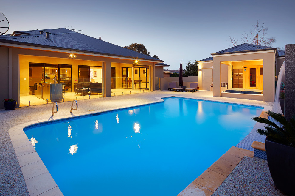 Ejemplo de piscina con fuente natural actual de tamaño medio rectangular en patio trasero