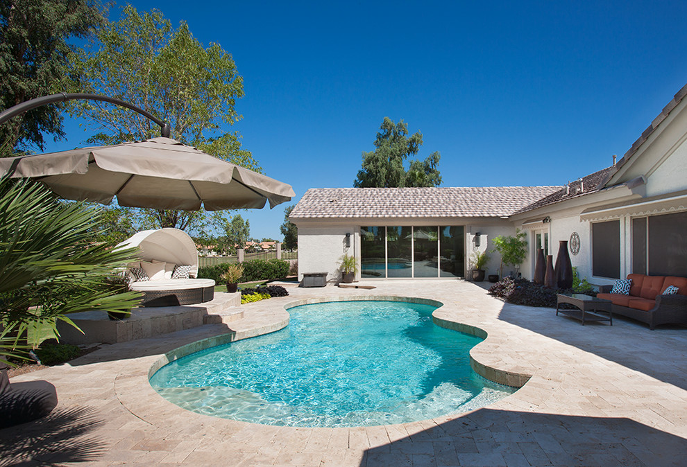 Foto de piscina tradicional de tamaño medio a medida en patio trasero con adoquines de piedra natural