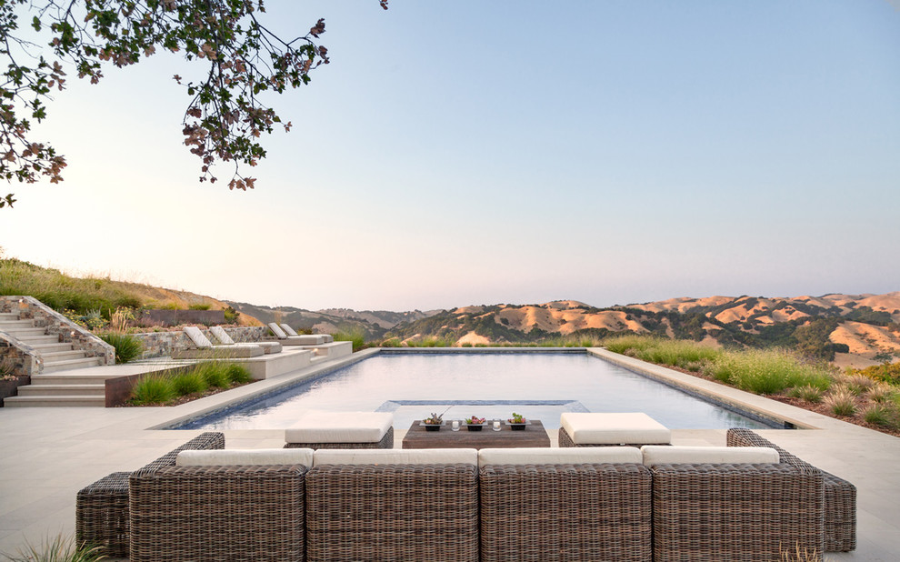 Ejemplo de piscina alargada contemporánea grande rectangular en patio trasero con adoquines de piedra natural