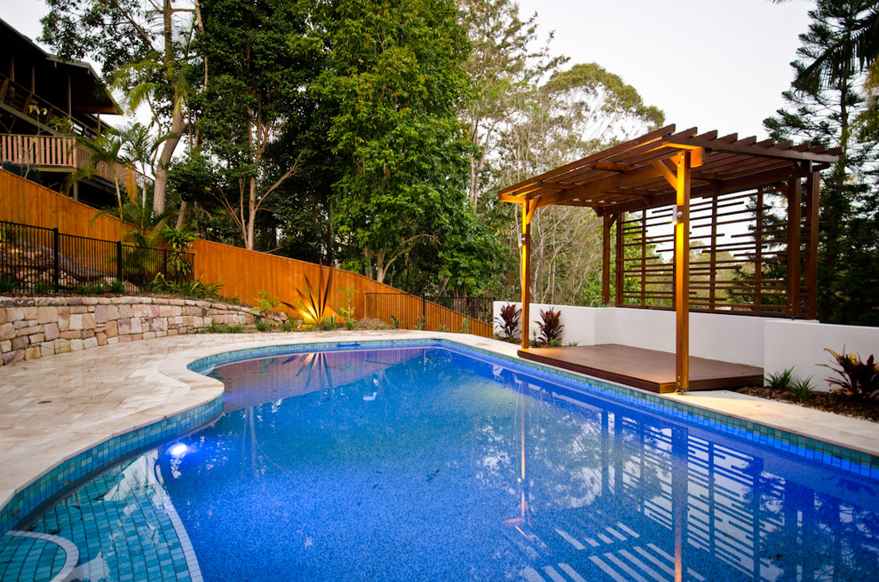 Ejemplo de casa de la piscina y piscina alargada contemporánea grande a medida en patio trasero con adoquines de piedra natural