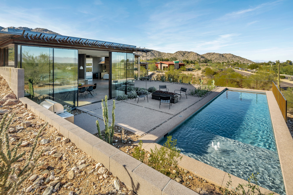 Foto de piscina alargada de estilo americano rectangular en patio trasero con losas de hormigón