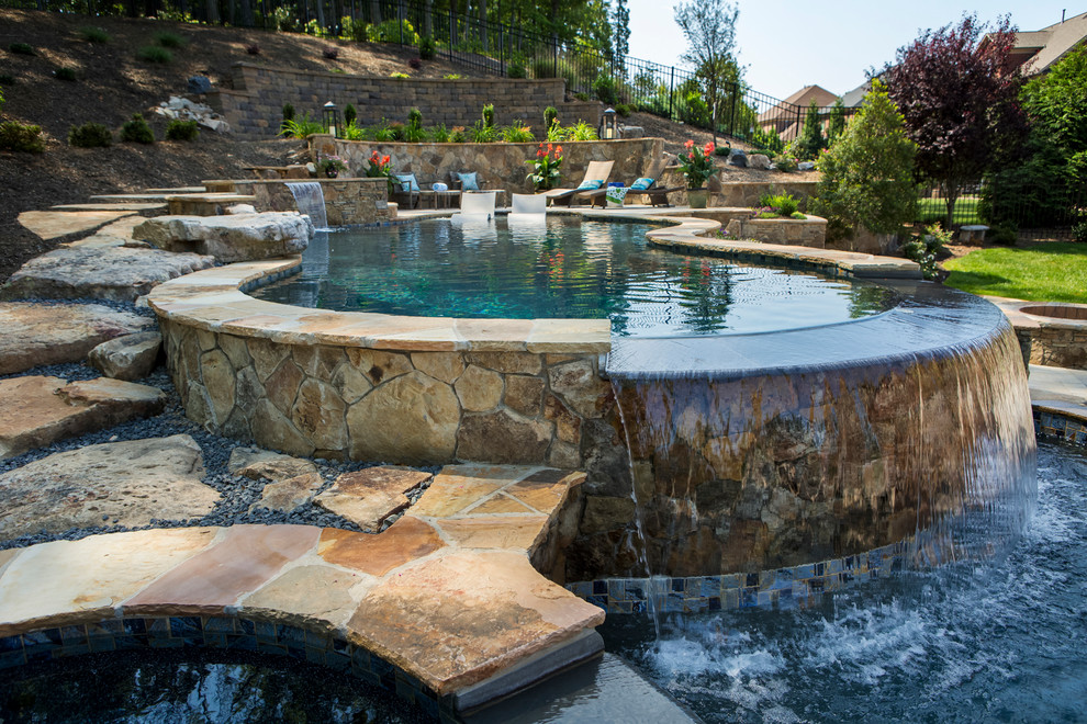 Inspiration for a large world-inspired back custom shaped natural swimming pool in Charlotte with a water feature and concrete paving.