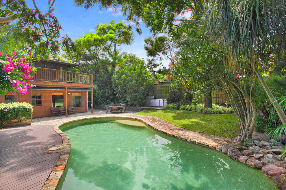 Imagen de piscina alargada exótica grande a medida en patio trasero con adoquines de ladrillo