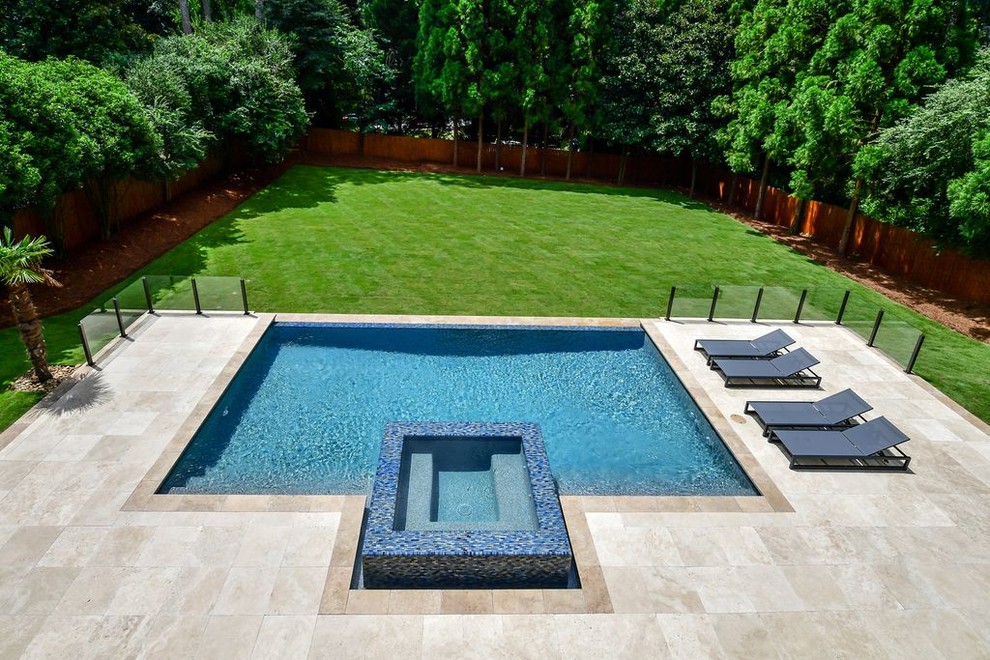 Ispirazione per una piscina a sfioro infinito moderna rettangolare di medie dimensioni e dietro casa con una vasca idromassaggio e pavimentazioni in pietra naturale