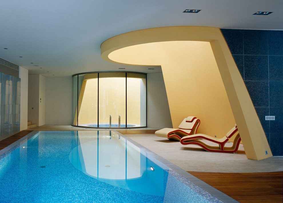 Cette image montre une grande piscine intérieure design rectangle avec un bain bouillonnant.
