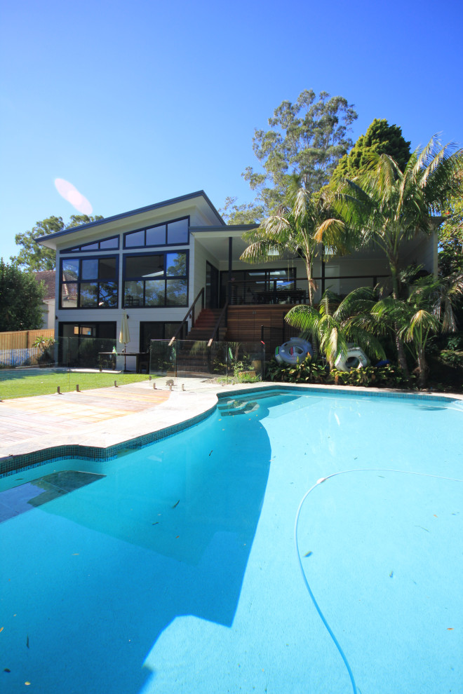 На фото: бассейн произвольной формы на заднем дворе в стиле модернизм с покрытием из каменной брусчатки с