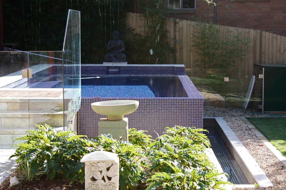 На фото: большой наземный, прямоугольный бассейн на заднем дворе в восточном стиле с настилом