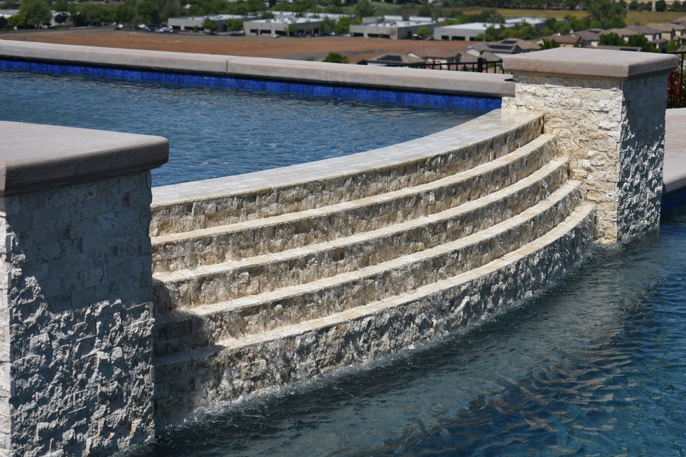 На фото: бассейн-инфинити среднего размера, произвольной формы на заднем дворе в современном стиле с покрытием из декоративного бетона с