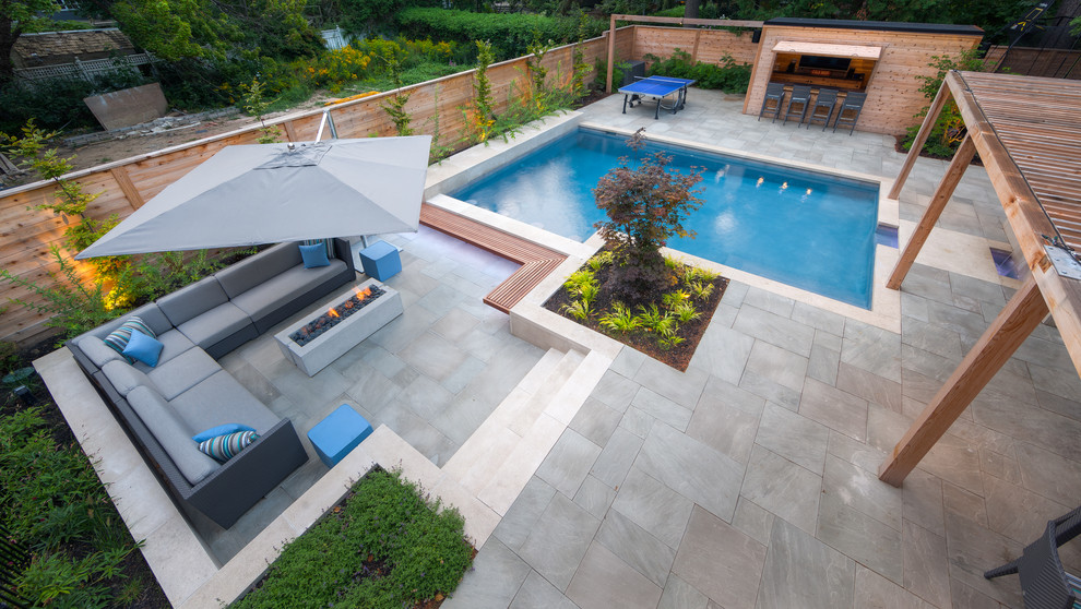 Стильный дизайн: большой прямоугольный бассейн на заднем дворе в современном стиле с домиком у бассейна и покрытием из каменной брусчатки - последний тренд