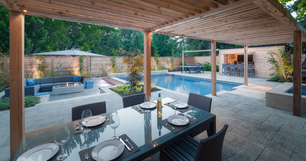 This is an example of a large contemporary back rectangular swimming pool in Other with a pool house and natural stone paving.